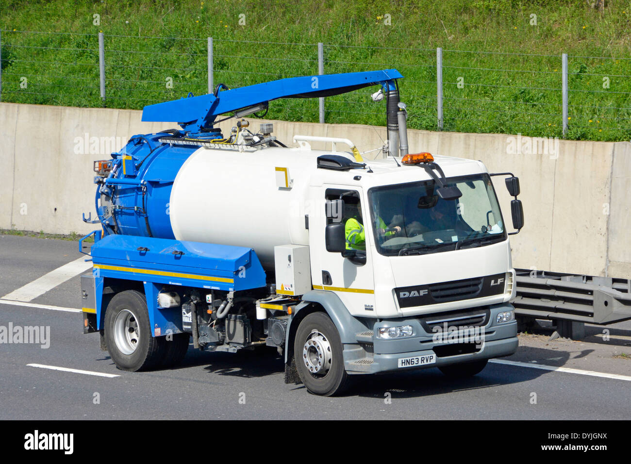 Driver of a clean blue and white DAF commercial vehicle road gully cleaning tanker lorry truck driving along M25 UK motorway Essex England UK Stock Photo
