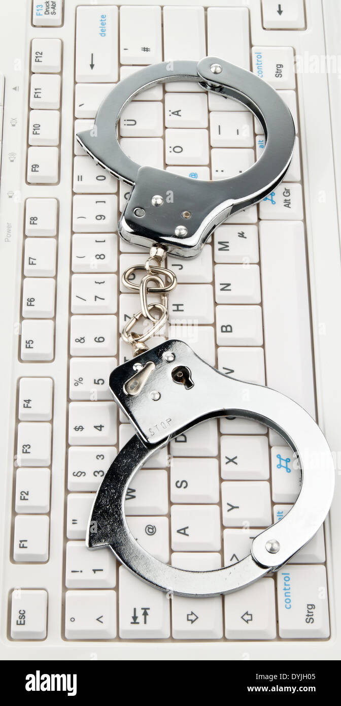 A computer keyboard and handcuffs. Cybercrime., Eine Computer Tastatur und Handschellen. Cyber Kriminalitaet. Stock Photo