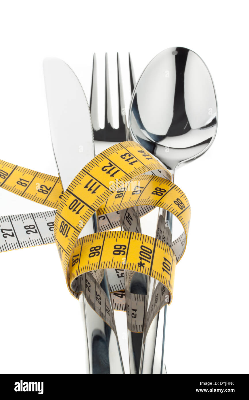 Cutlery with measuring tape. Symbol for diet and weight loss., Gelbes Massband um Besteck gewickelt / Symbolfoto Abnahmen Stock Photo