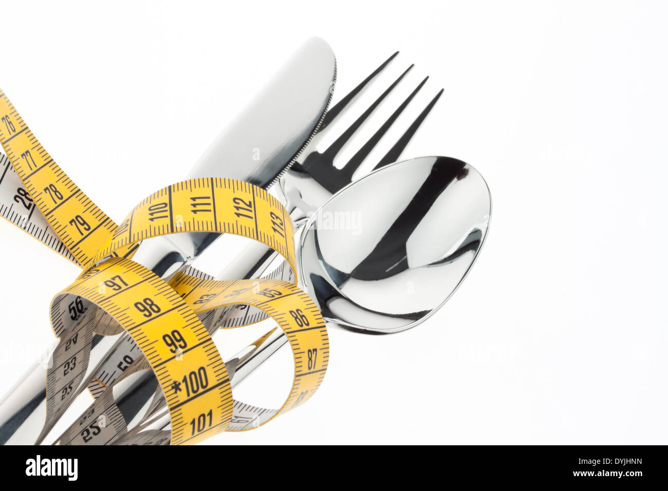 Cutlery with measuring tape. Symbol for diet and weight loss., Gelbes Massband um Besteck gewickelt / Symbolfoto Abnahmen Stock Photo