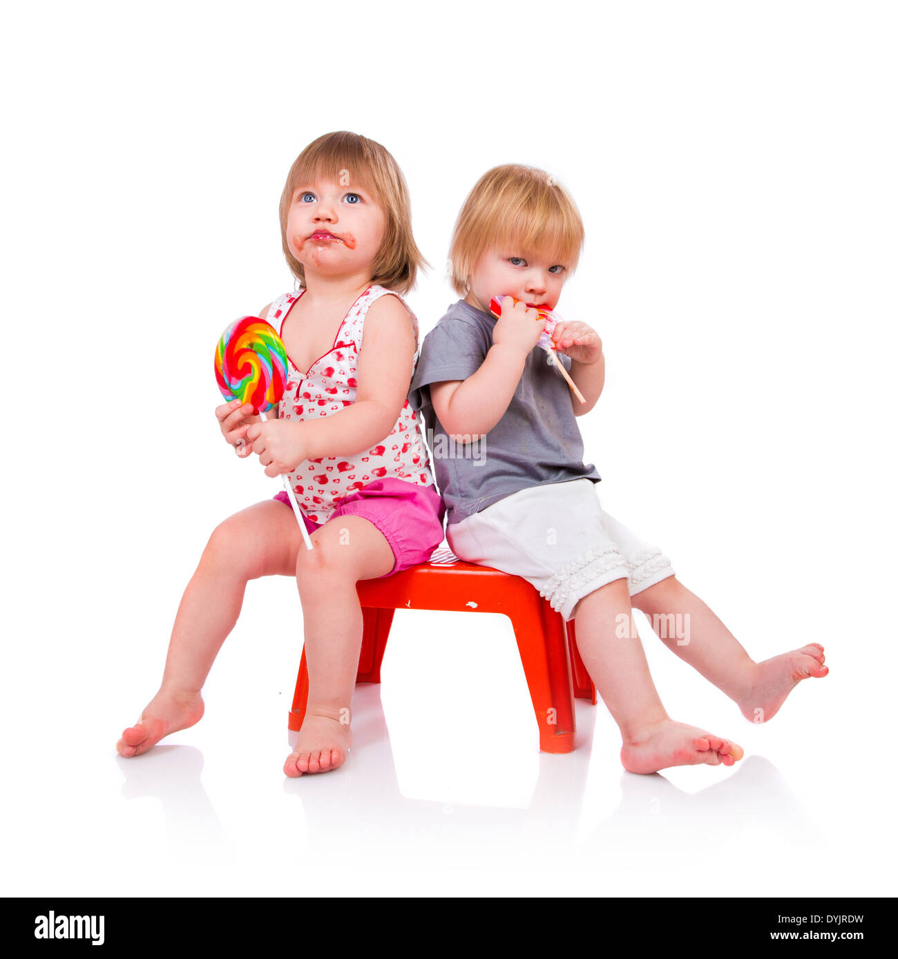 Babies eating a sticky lollipop on white background Stock Photo