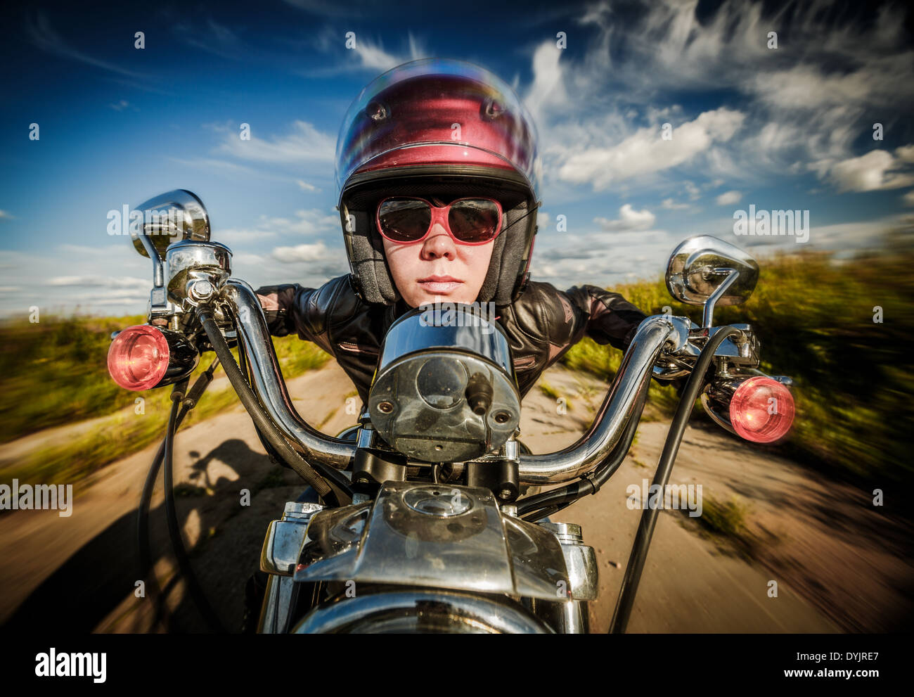 Funny Biker girl in sunglasses and leather jacket racing on the road (fisheye lens) Stock Photo