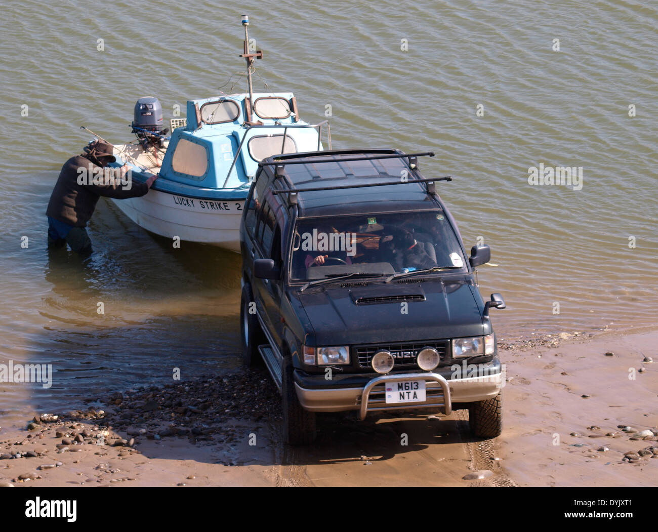 Husband and wife bring a boat out of the water on a trailer, Bude, Cornwall, UK Stock Photo