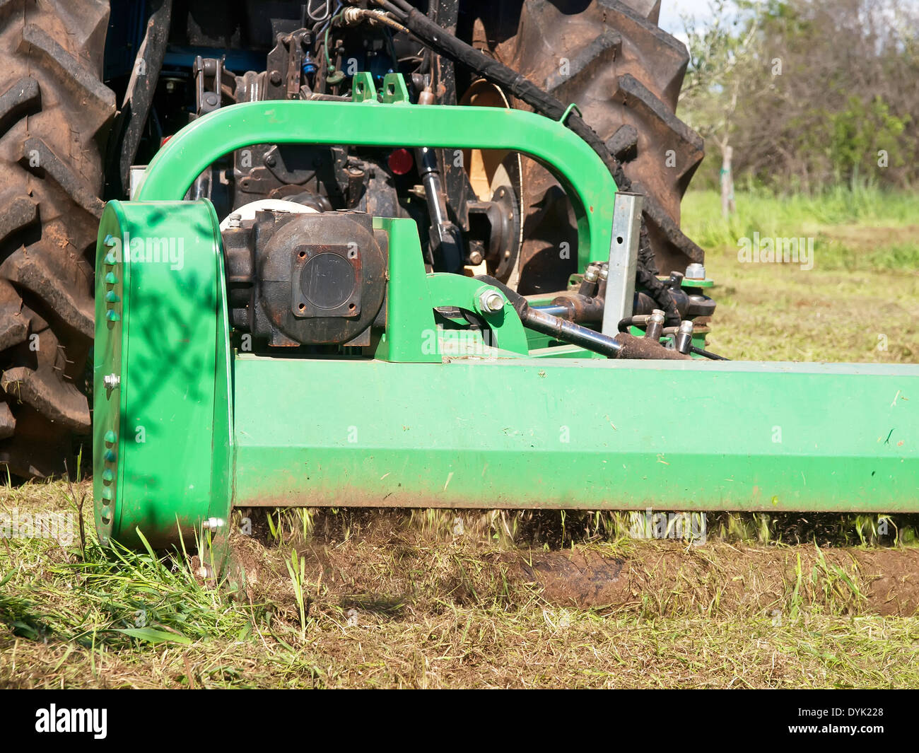 tractor machine lawnmower cutting grass along ground field Stock Photo
