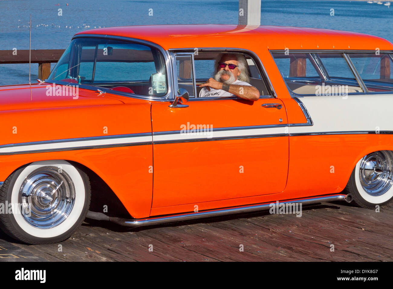 Old hippy driving a bright red 1956 Chevrolet station wagon on Stern's Wharf in Santa Barbara, California Stock Photo