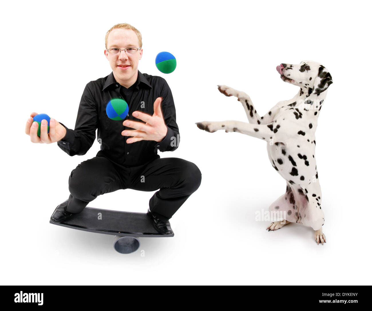 young man juggling with balls and balancing on a rola bola balance board, Mann spielt mit Dalmatiner Stock Photo
