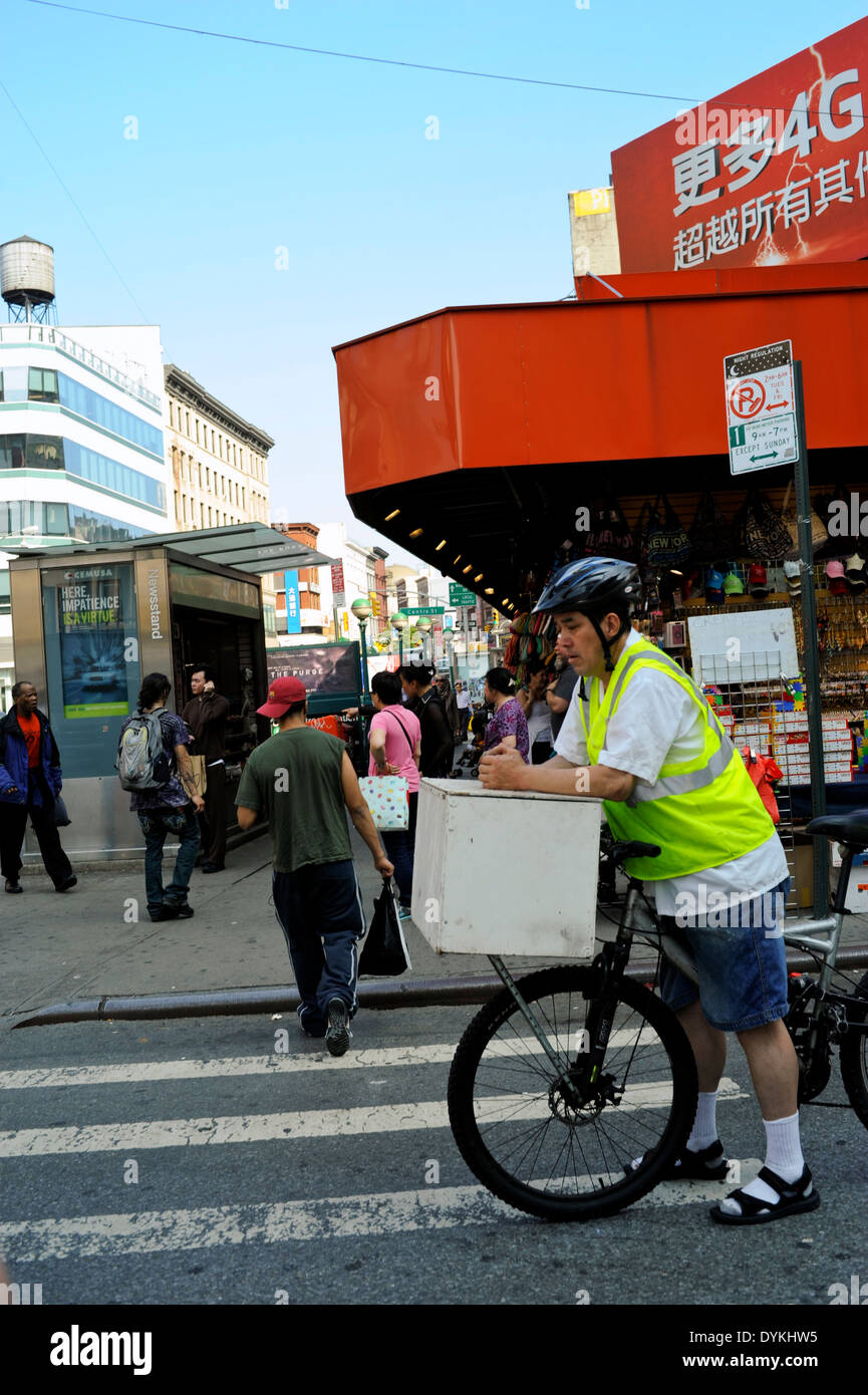 Bicycle delivery man on bike at intersection, Chinatown, New York City Stock Photo
