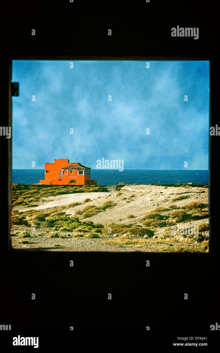 Orange house seen through a window frame with sea and sky behind. Sky and colours altered in photoshop. Original DYKJ8P Stock Photo