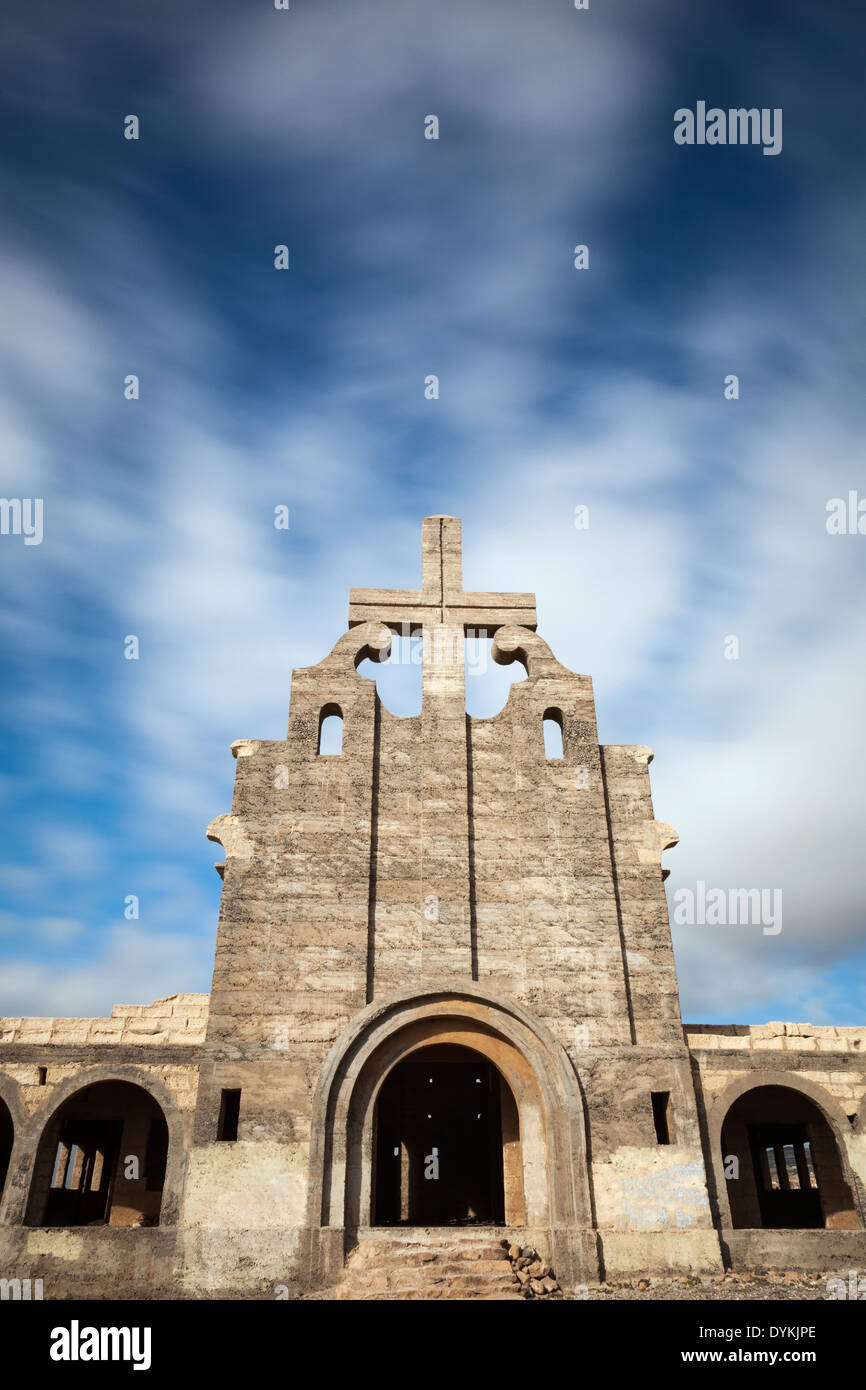 Abandoned derelict old church front with concrete cross photographed with 10 stop ND filter to allow movement in the clouds. Stock Photo