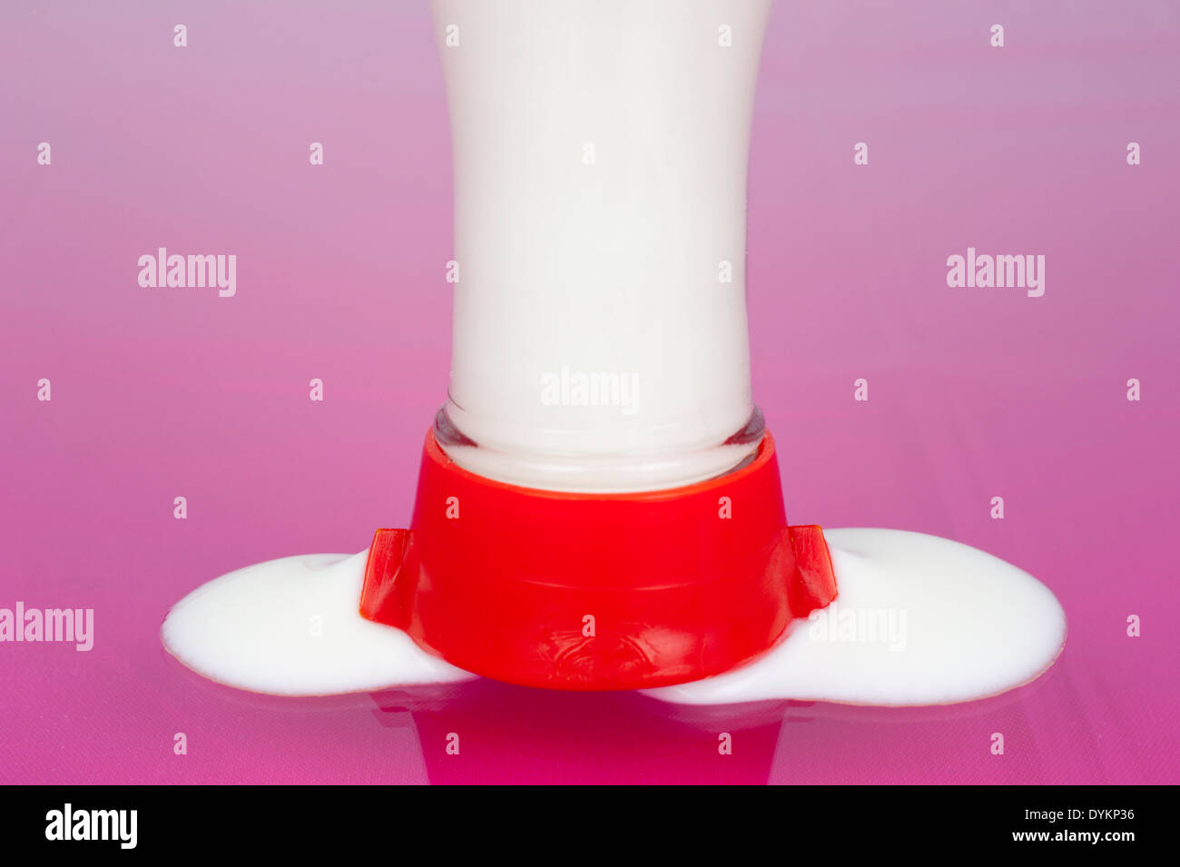 Milk filled bottle running empty on pink floor Stock Photo