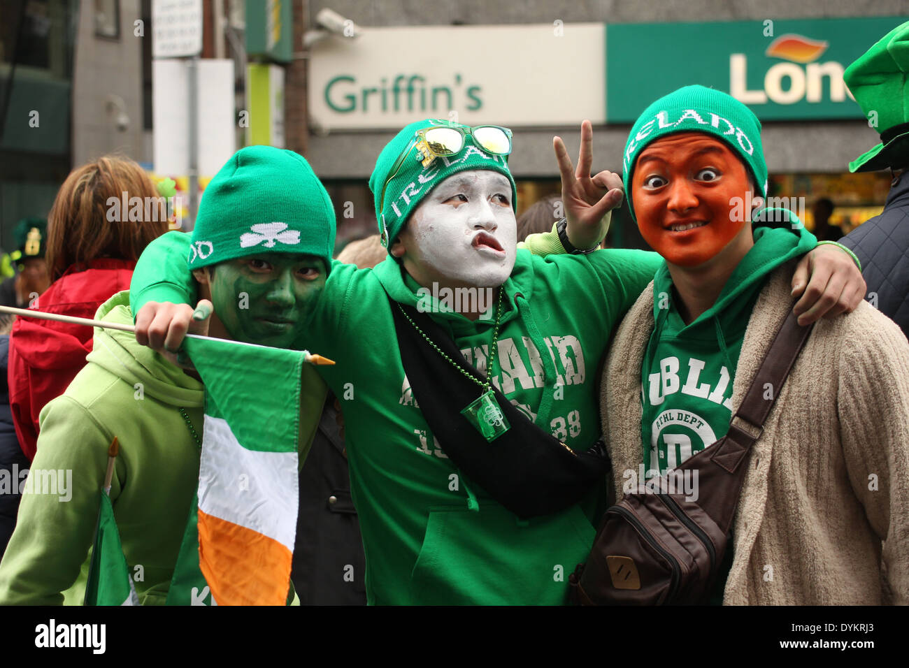 Three men dressed up with green, white, and orange face paint for the