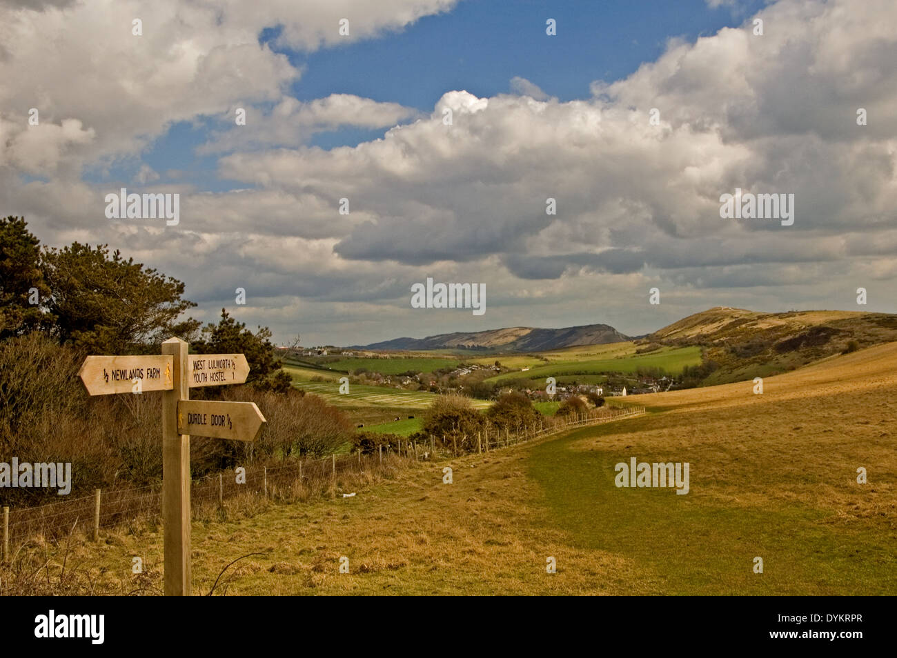 A timber directional sign pointing the way to Durdle Door, with the Purbeck Hills in the background. Stock Photo