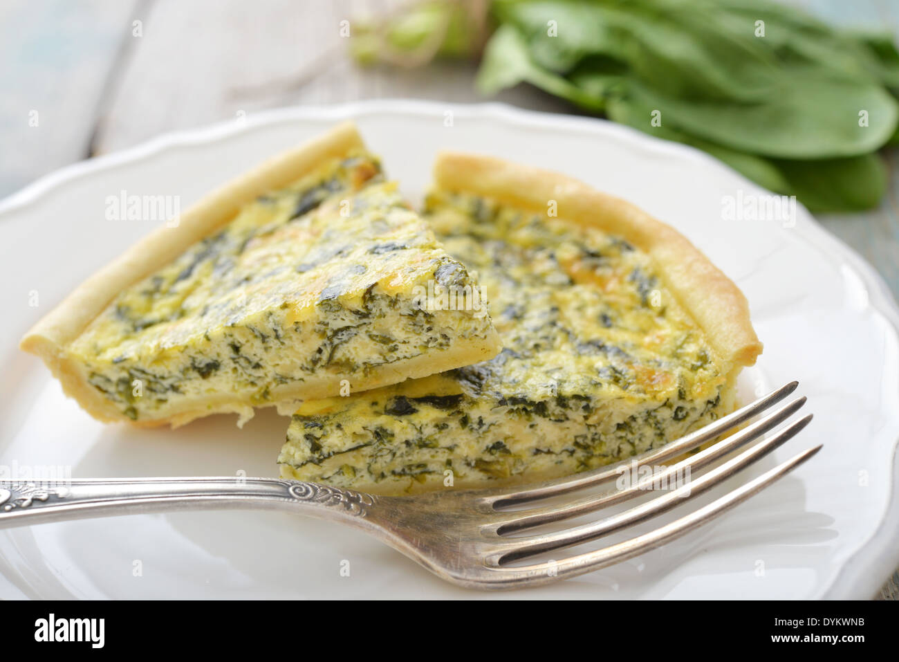 Traditional french quiche pie with spinach and cheese on white plate