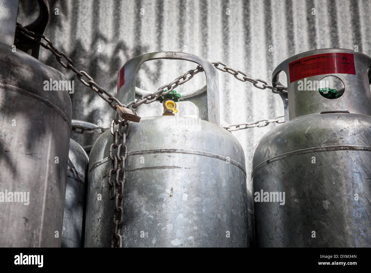 Some gas bottles chained and padlocked against a galvanized steel wall