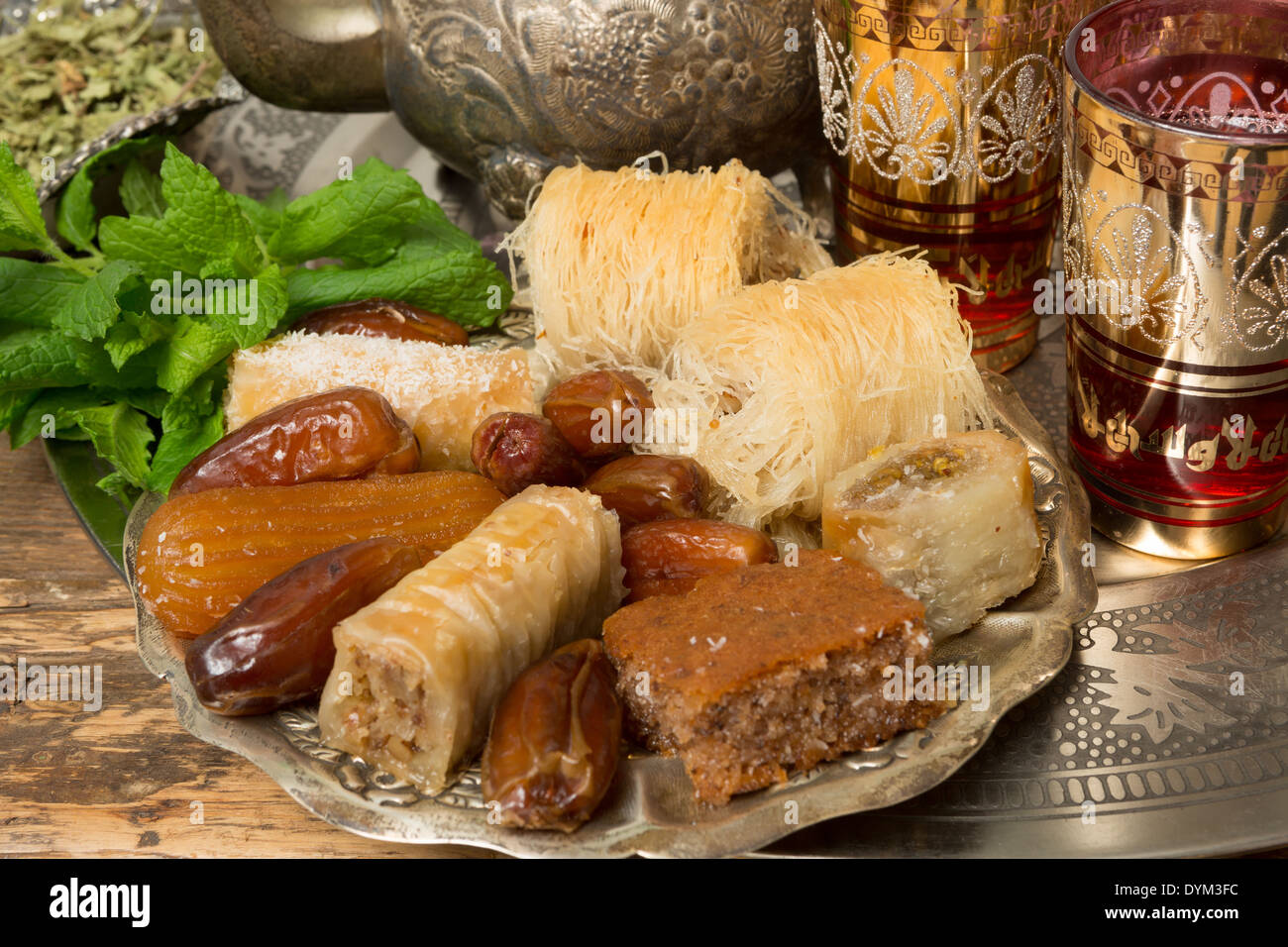 Oriental sweet cookies, tea cups and mint leaves on a Moroccan tea tray