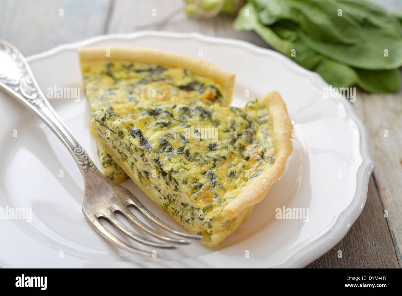 Traditional french quiche pie with spinach and cheese on white plate