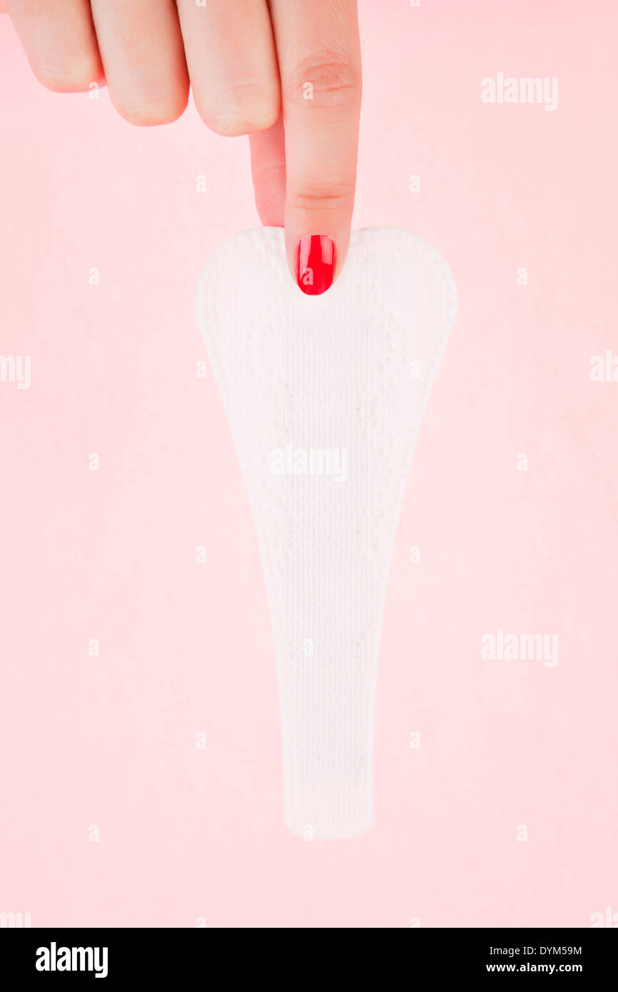 Female hand with red fingernails holding clean g - string pantyliner. Feminine hygiene concept. Stock Photo
