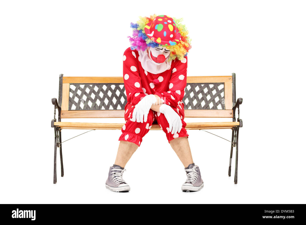 Sad clown sitting on a wooden bench Stock Photo