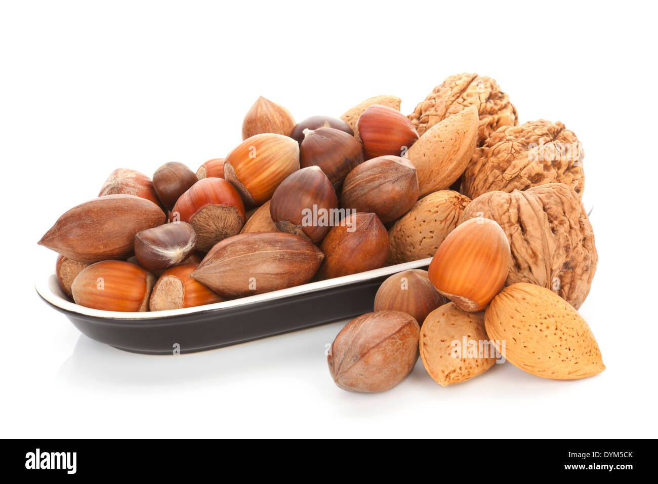 Various nuts, walnuts, hazelnuts, almond and chestnuts in black bowl isolated on white background. Seasonal healthy nuts. Stock Photo