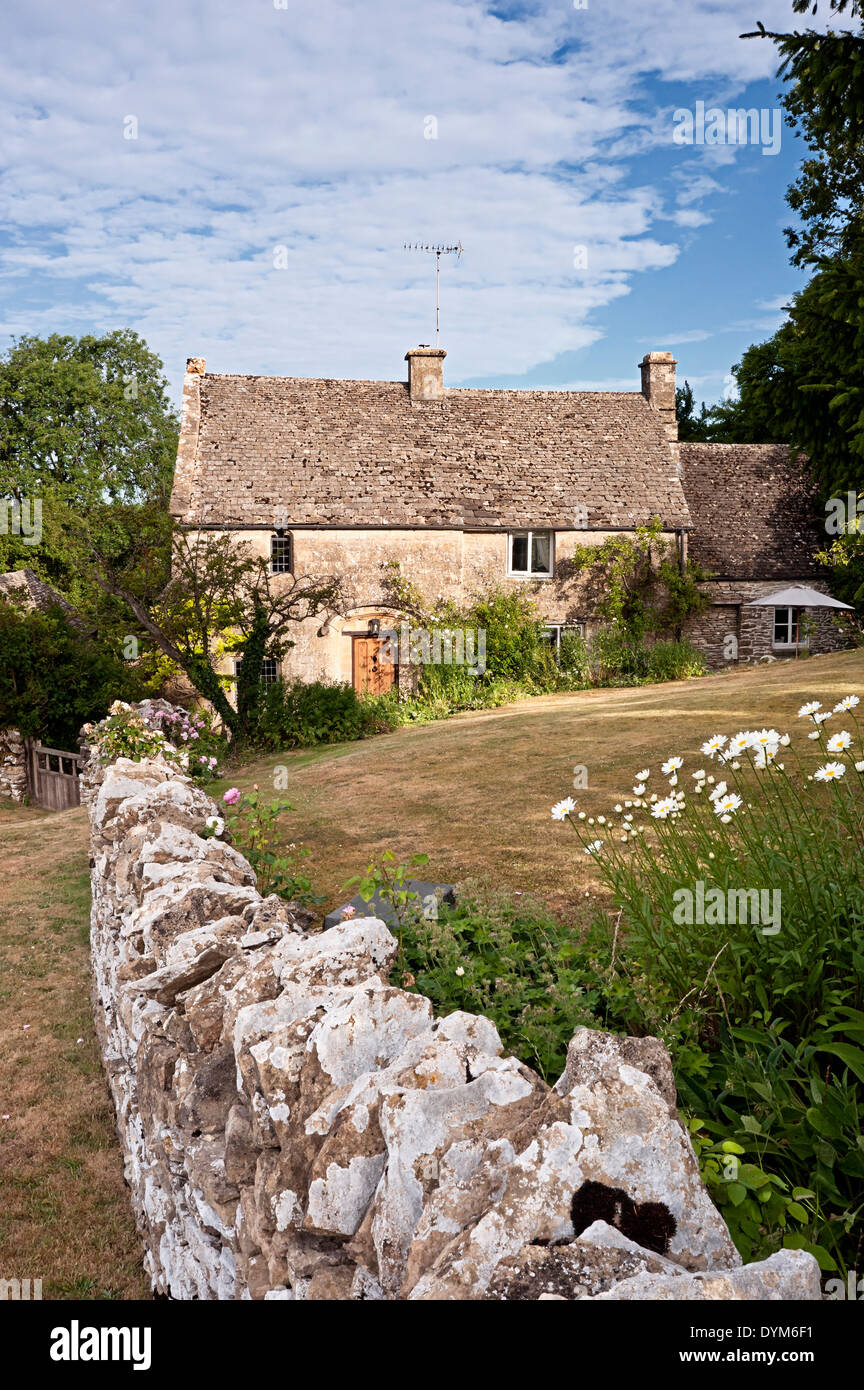 Cotswold stone cottage with wall and garden in summer Stock Photo