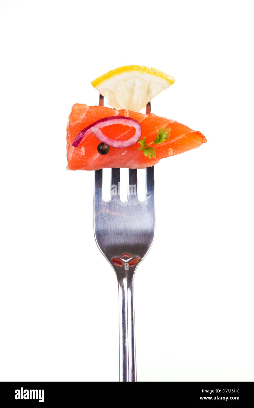 Salmon piece with lemon, onion, pepper corn and herb arranged on fork. Stock Photo