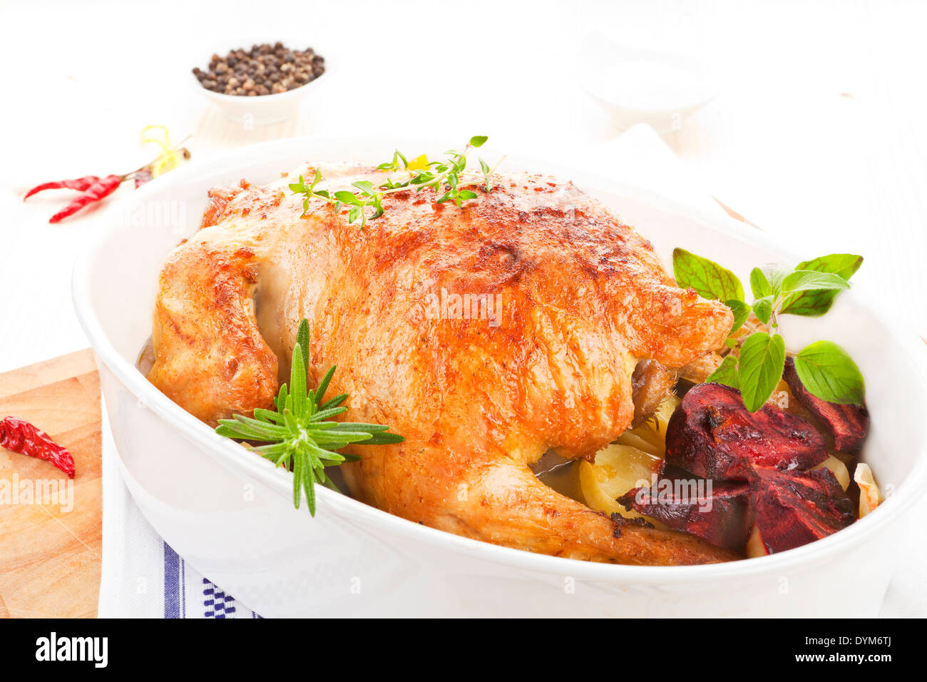 Delicious golden grilled whole chicken with fresh herbs in baking dish