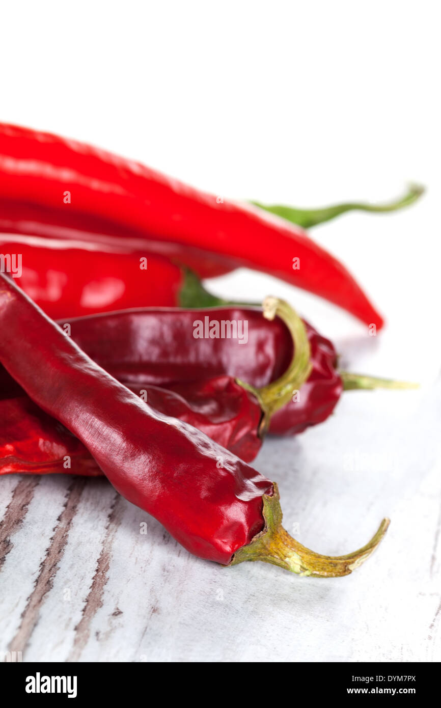Red hot chili peppers isolated on white wooden textured background. Culinary hot spices. Stock Photo