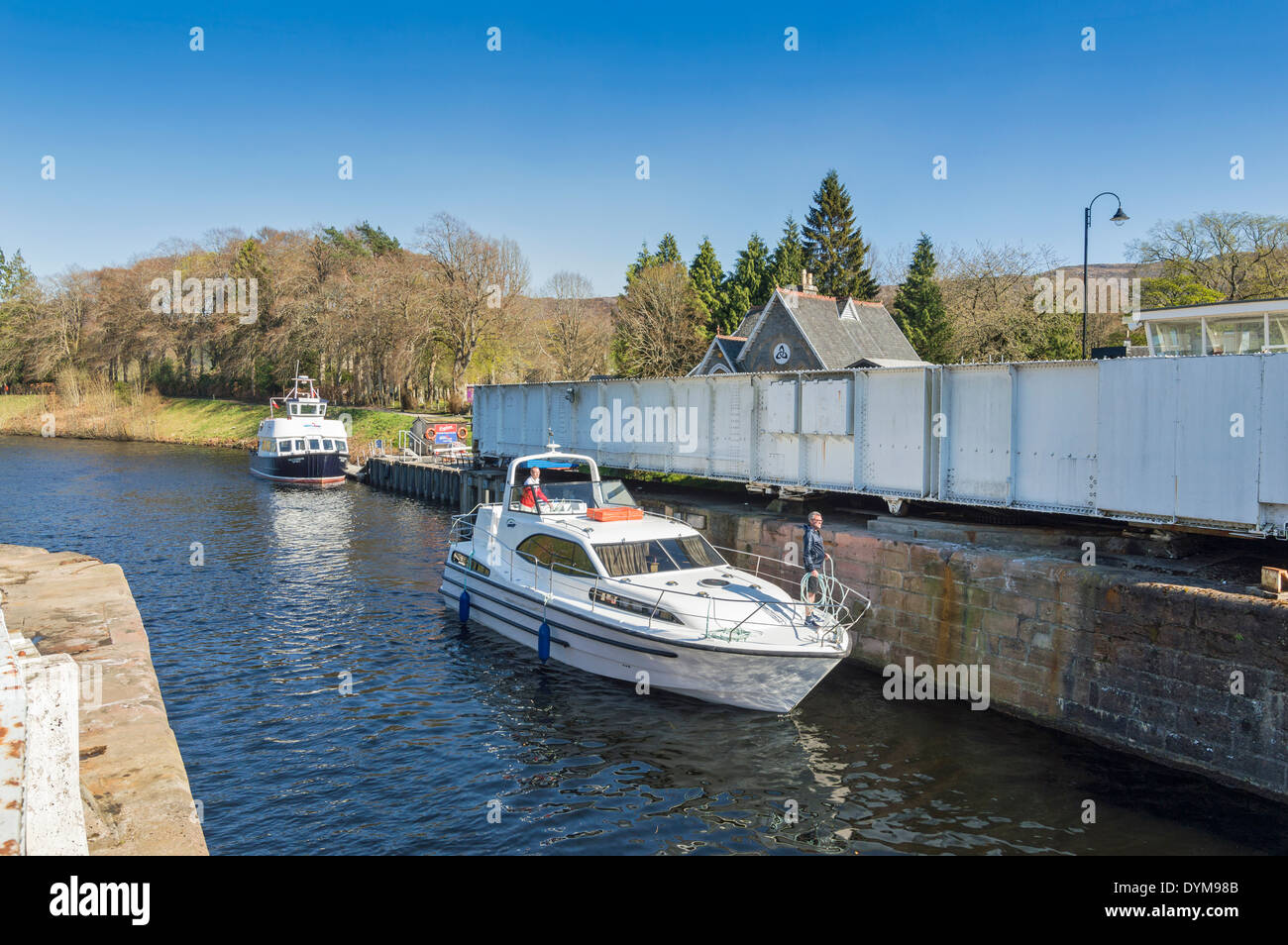 BOAT PASSING THROUGH THE  CALEDONIAN CANAL AT FORT AUGUSTUS LOCH NESS WITH THE A 82 ROAD SWING BRIDGE OPEN Stock Photo