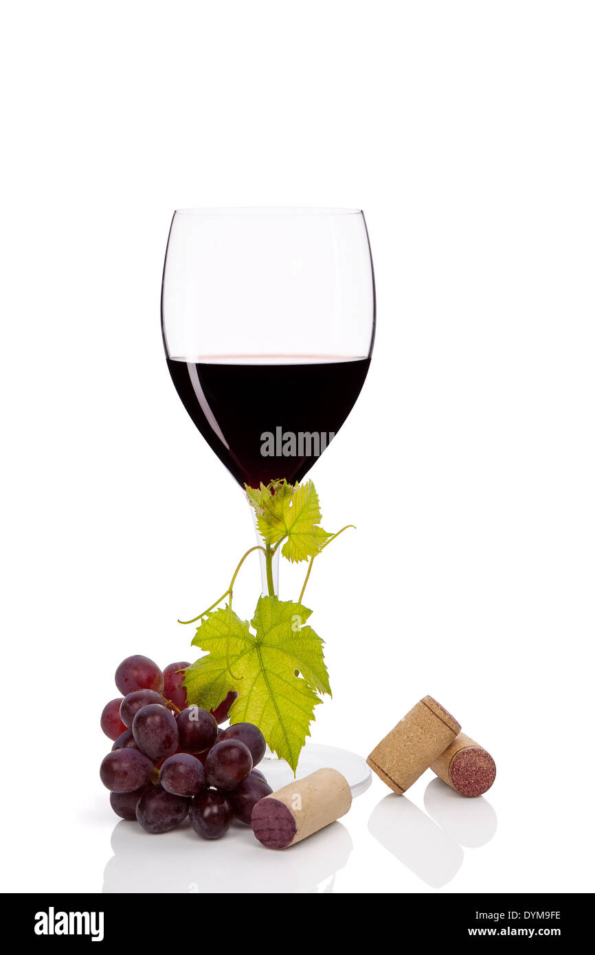 Red wine in wine glass with red grapes and various wine corks isolated