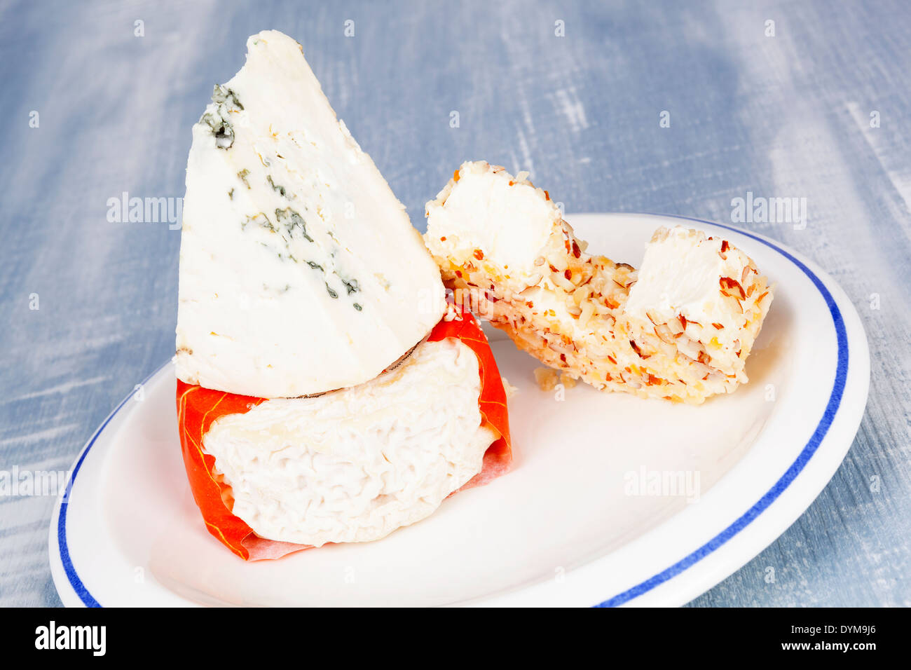 Luxurious colorful cheese assortment. Blue cheese, cream cheese and goat cheese on plate on blue wooden background. Culinary Stock Photo