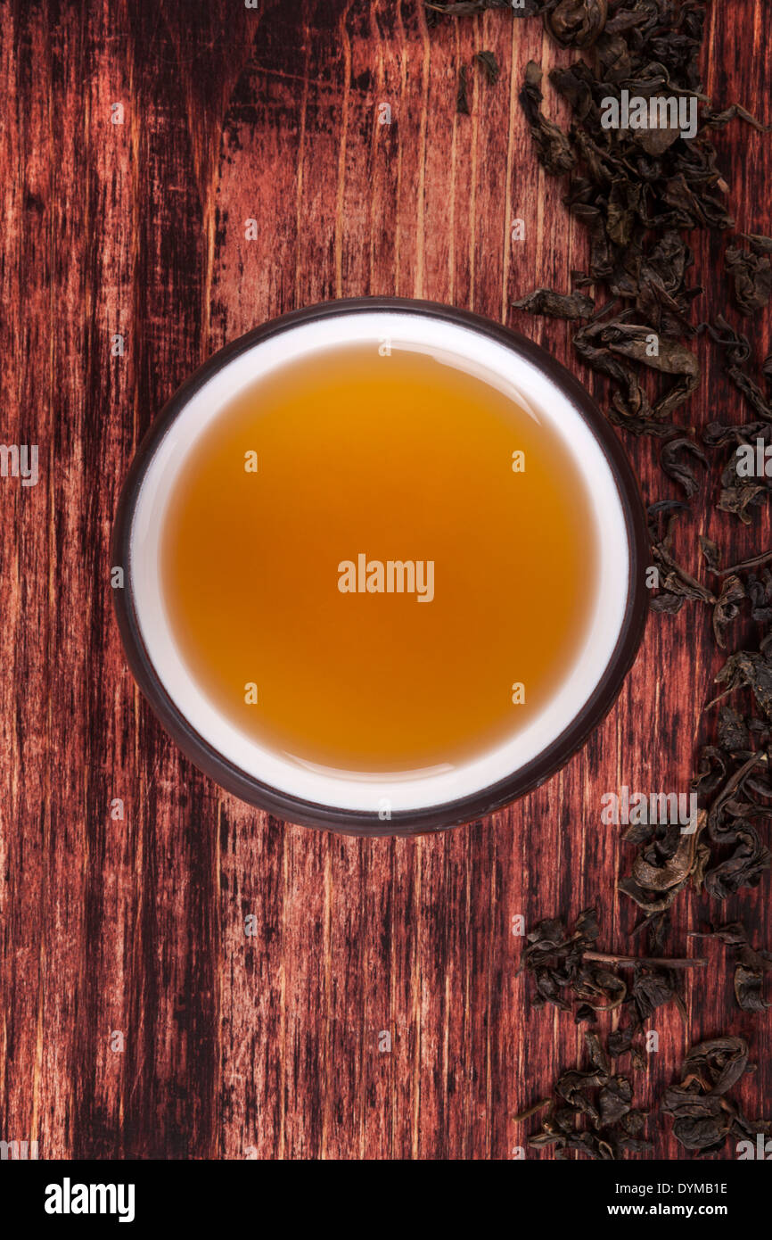 Traditional tea drinking. Dry tea crop, green tea in cup on brown