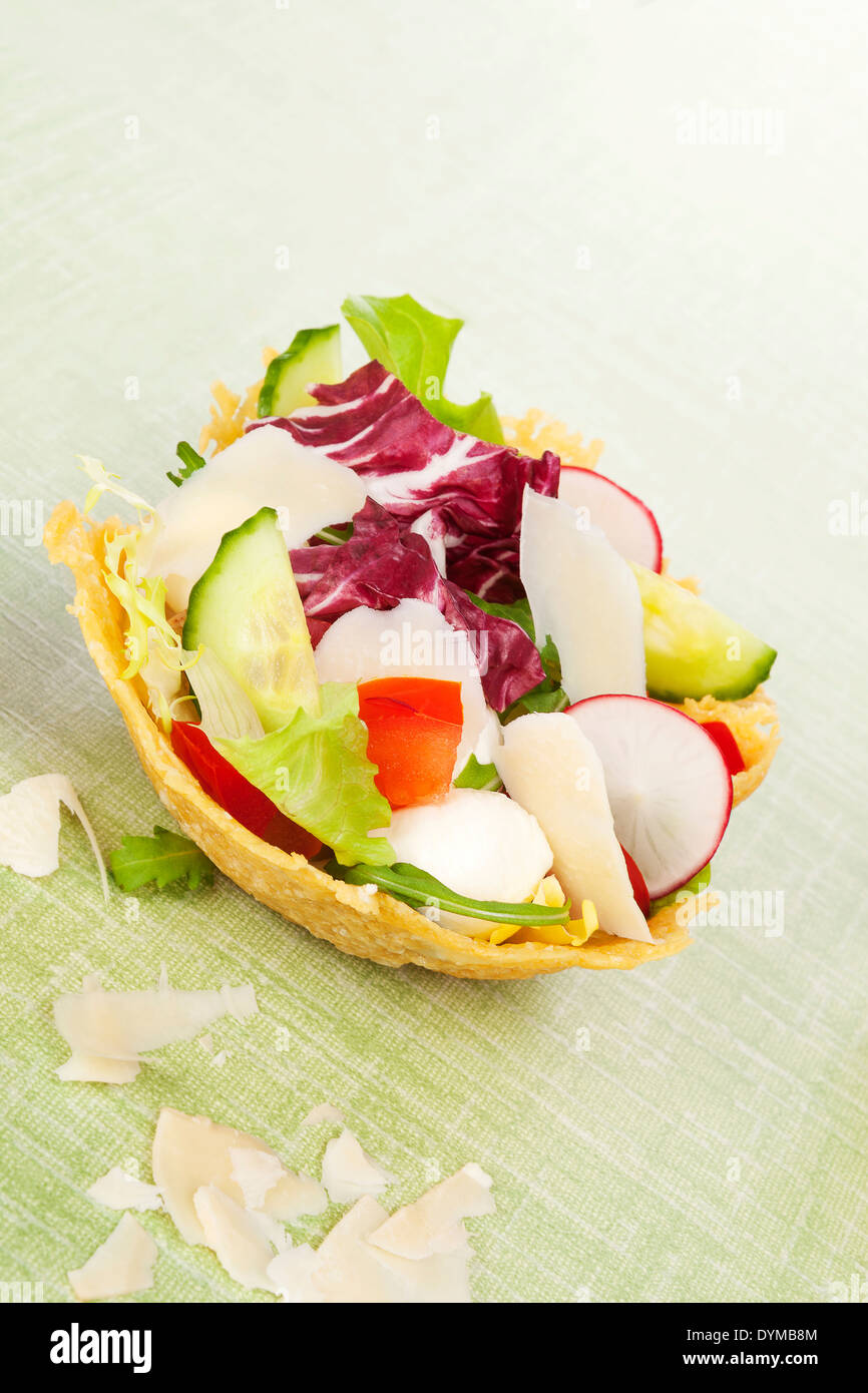 Cheese basket filled with fresh vegetable salad and bacon. Culinary