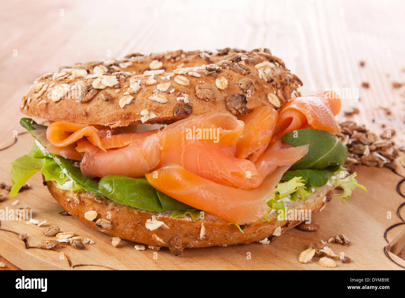 Whole grain bagel with smoked salmon on wooden background. Culinary healthy bagel eating. Stock Photo