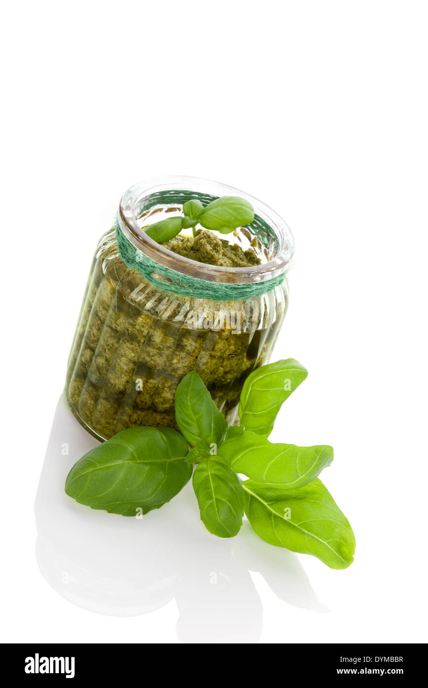 Green basil pesto in glass jar isolated on white background. Healthy
