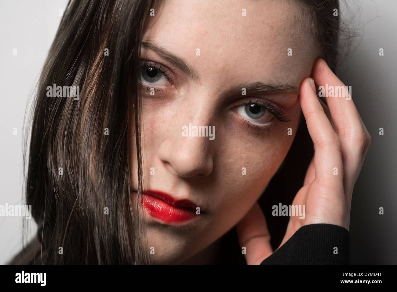 Young attractive woman with red lipstick and hand to face Stock Photo