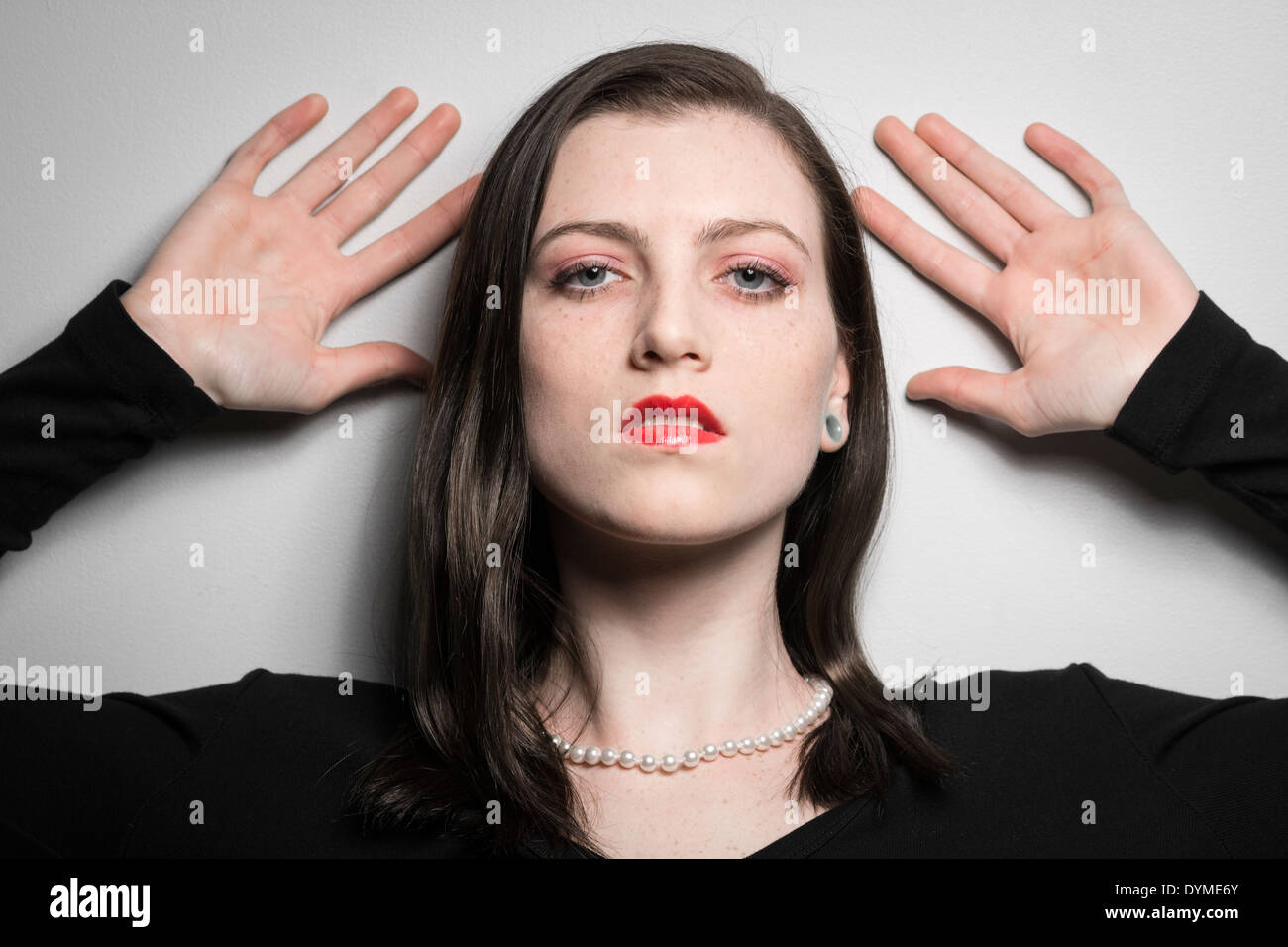 Young female model with hands on wall and red lipstick Stock Photo