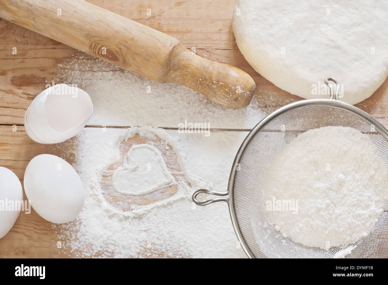 Flour, dough, eggs and rolling-pin on wooden table. Stock Photo