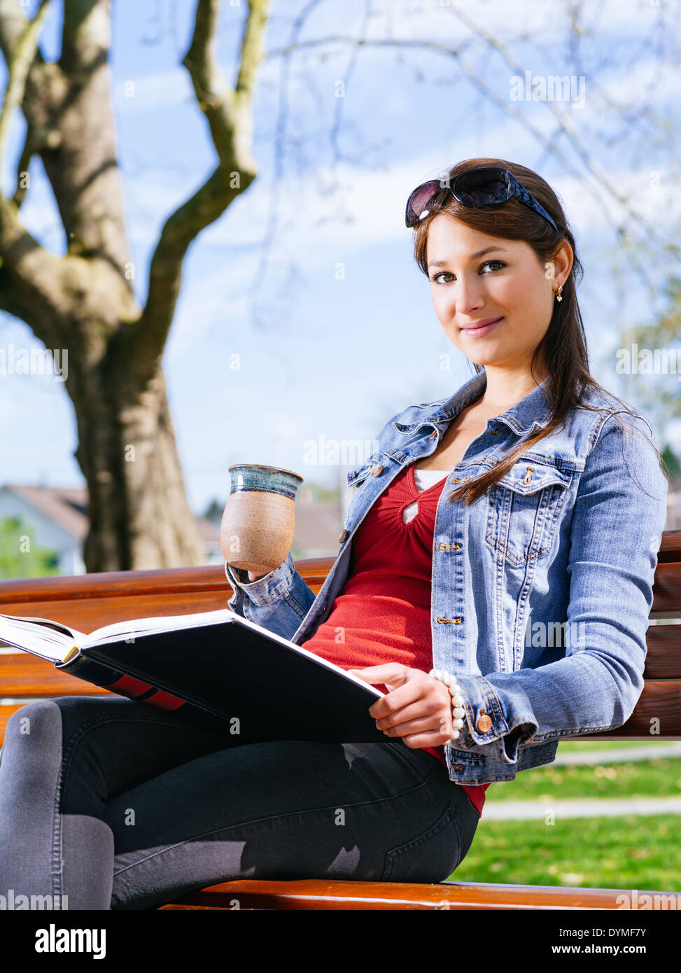 Photo of a beautiful young woman enjoying coffee and reading a book ...