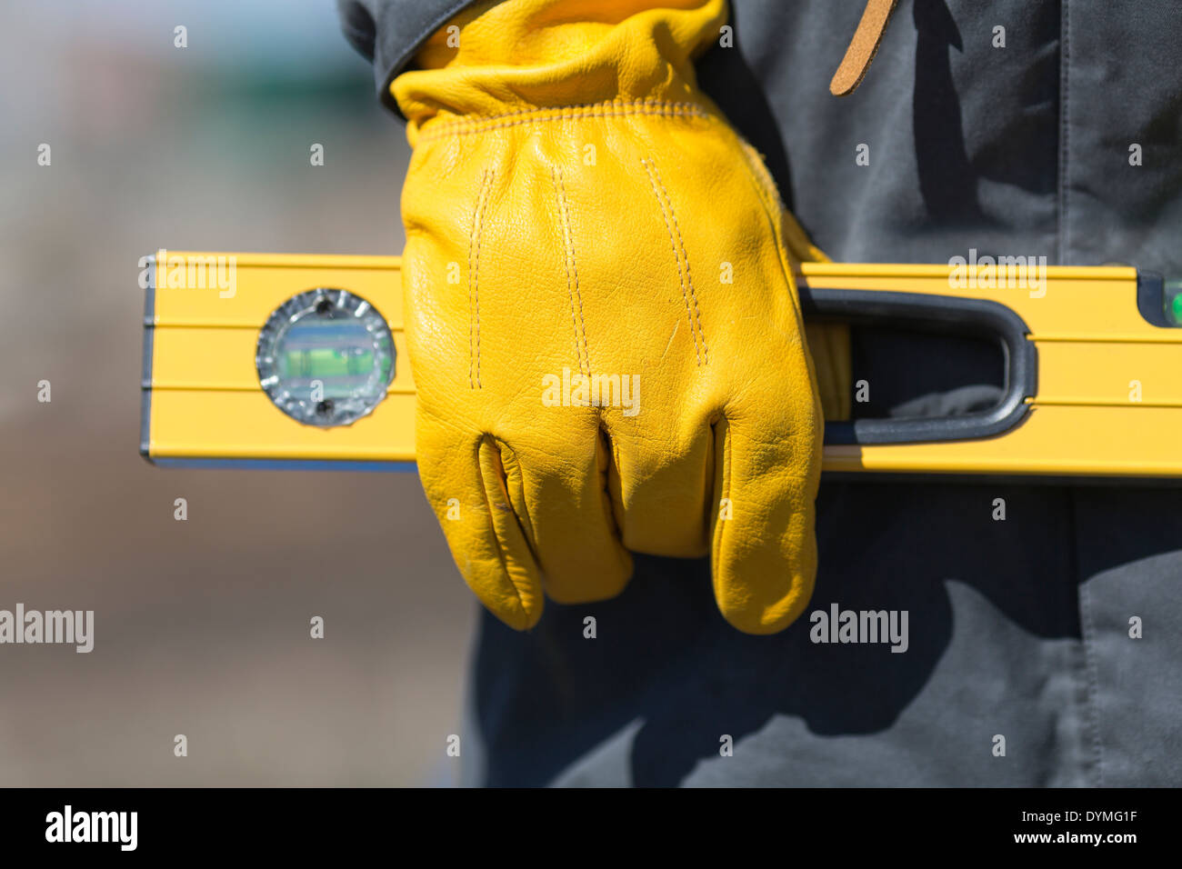 hand of worker with yellow glove and level Stock Photo - Alamy