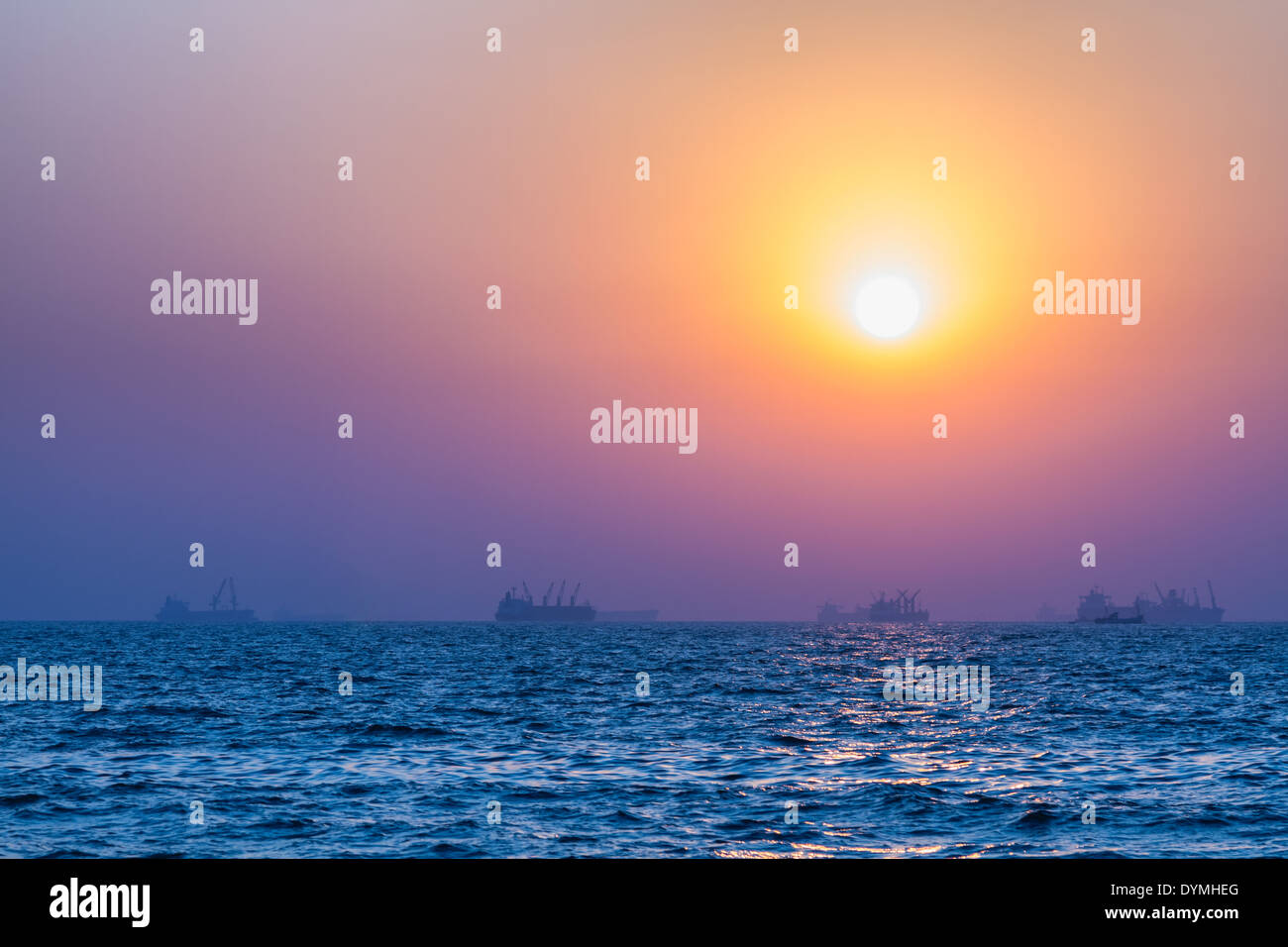 Scenic view of beautiful sunset above the Arabian sea. Cargo ship on the background Stock Photo