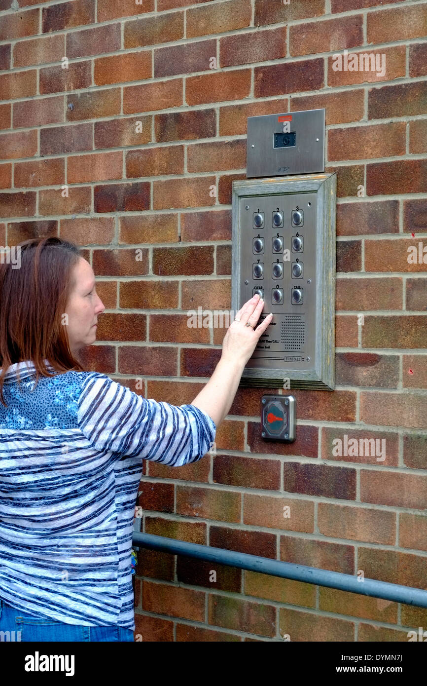 A middle aged woman using a tunstall secure door entry control system to  enter an old peoples housing complex Stock Photo - Alamy