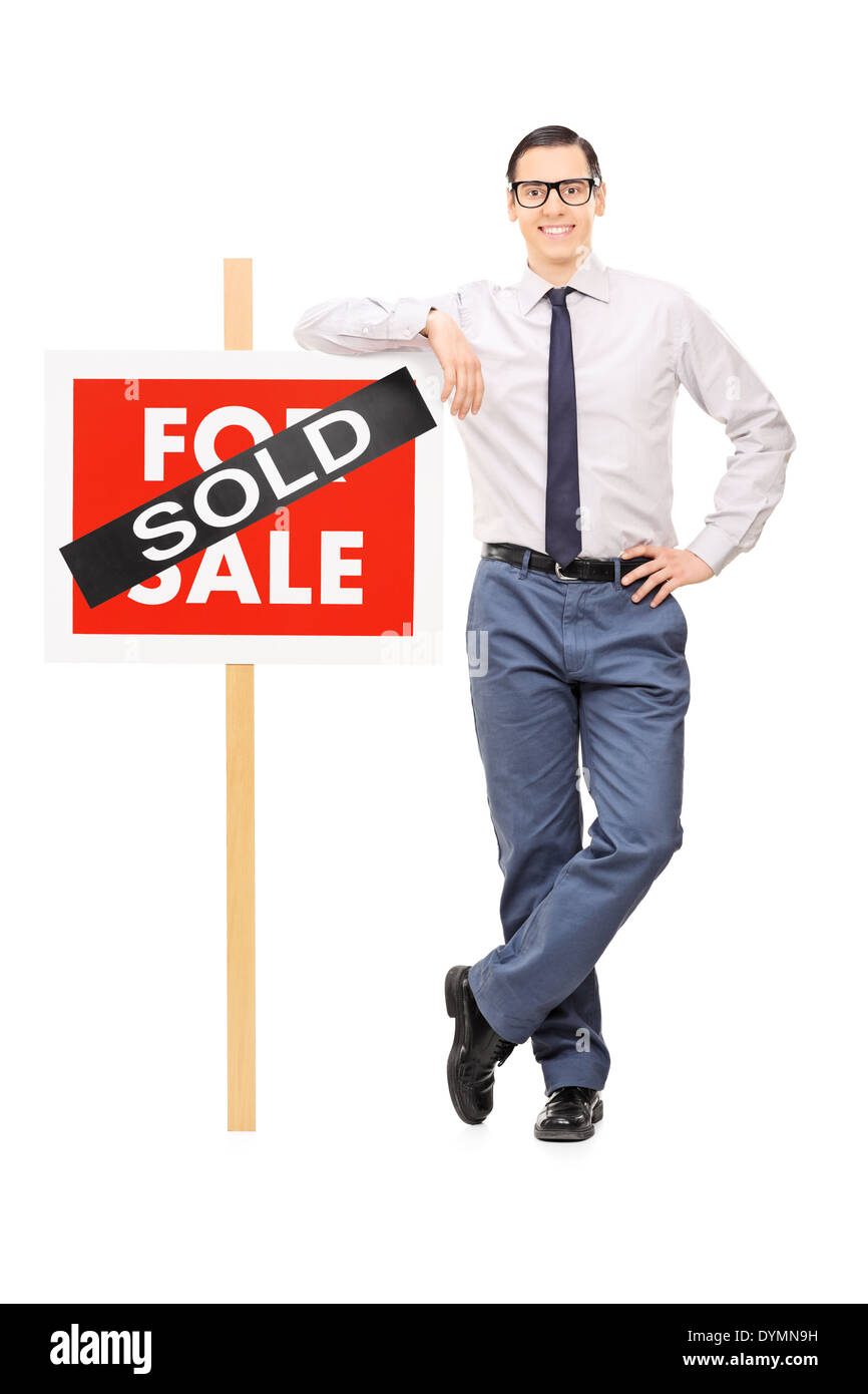 Male real estate agent leaning on a sold sign Stock Photo