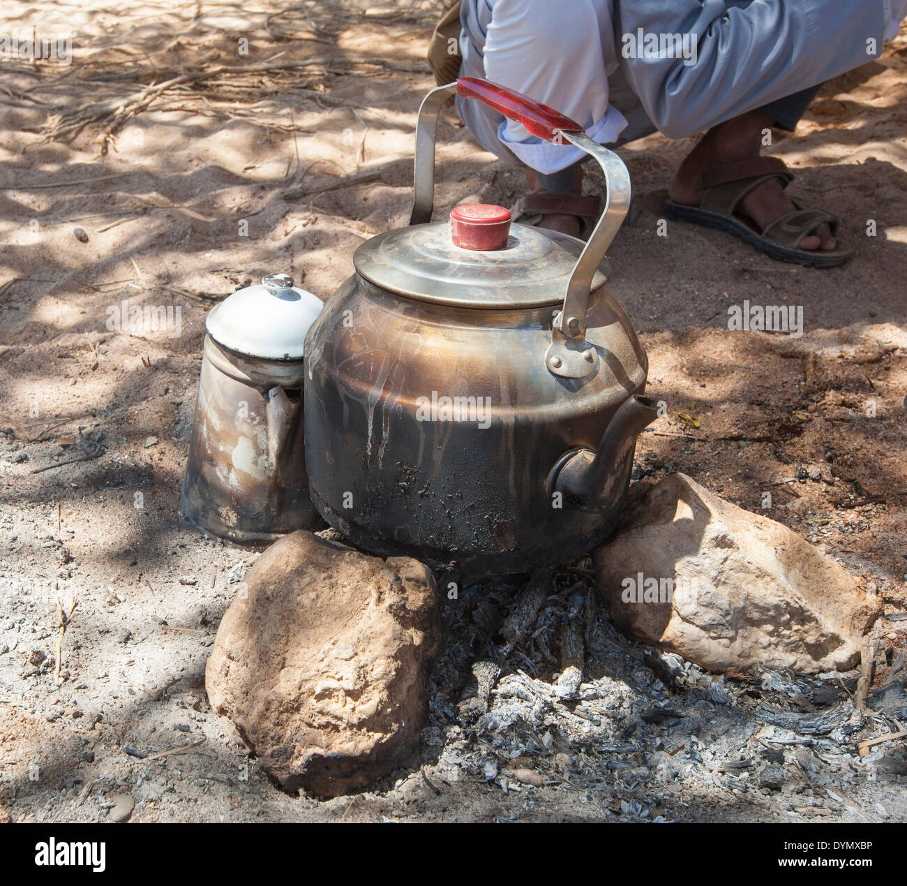 https://c8.alamy.com/comp/DYMXBP/traditional-kettle-on-camp-fire-in-desert-with-local-bedouin-man-DYMXBP.jpg