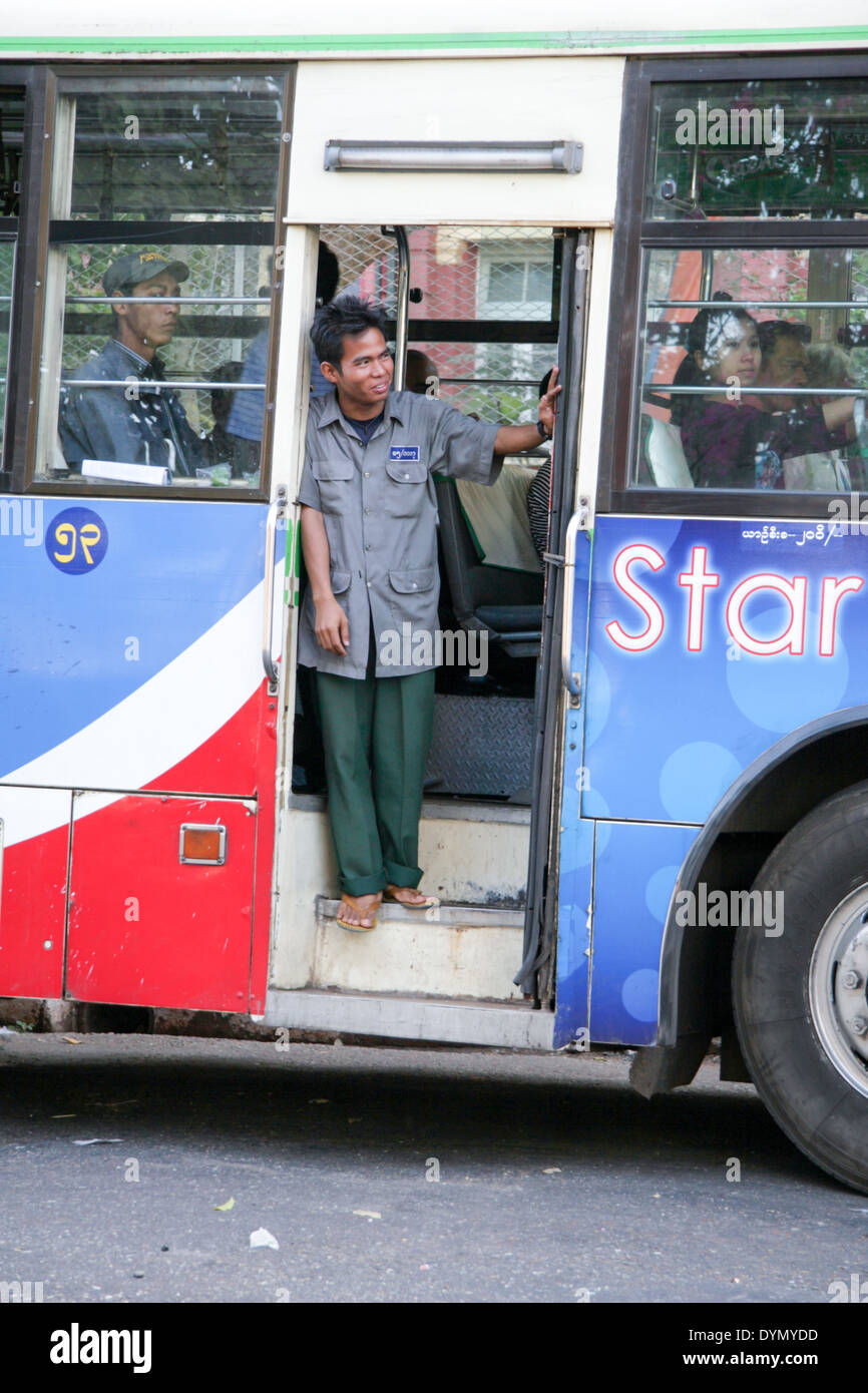 Bus conductor touting for business on the street of Yangon. Myanmar Stock Photo