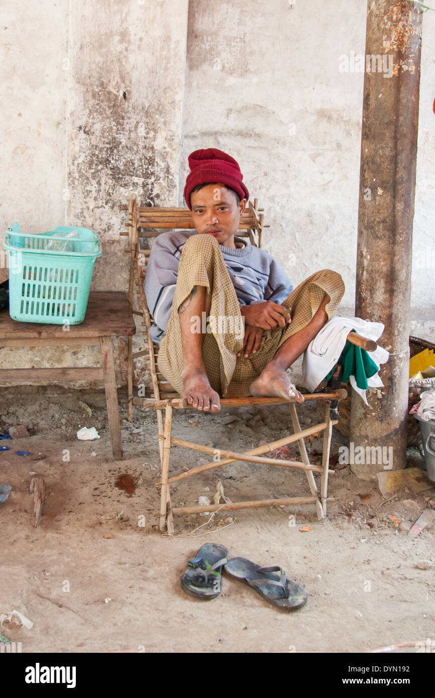 Man sat next to his stall in Mandalay Burma Stock Photo