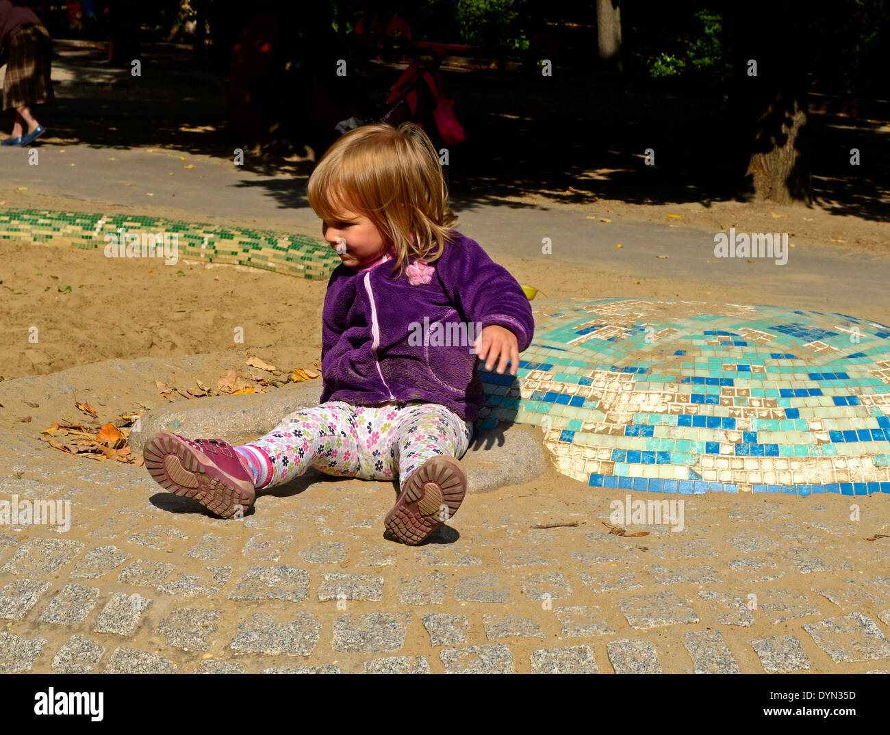 Little girl on the playground sitting on the hillside Stock Photo