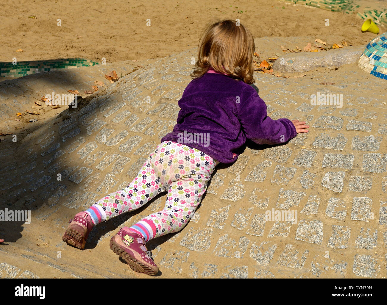 Little girl on the playground is prone on the hillside Stock Photo