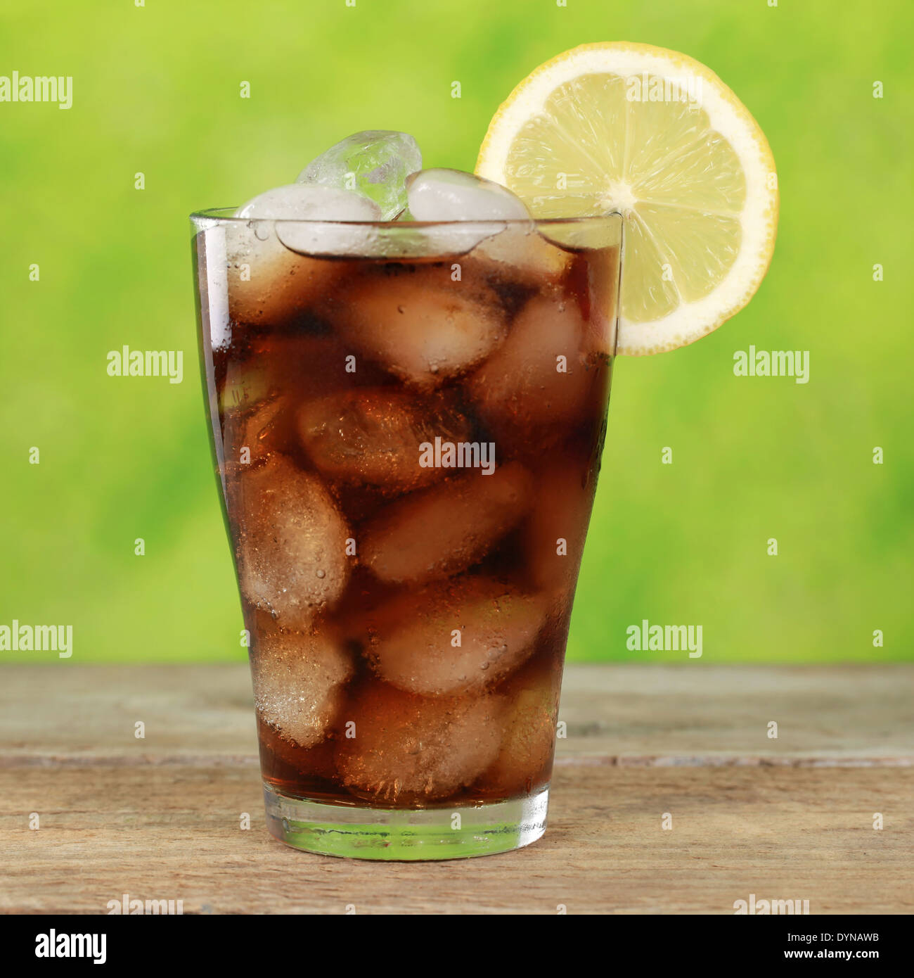 Cola drink in a glass with ice cubes, served with a slice of lemon ...