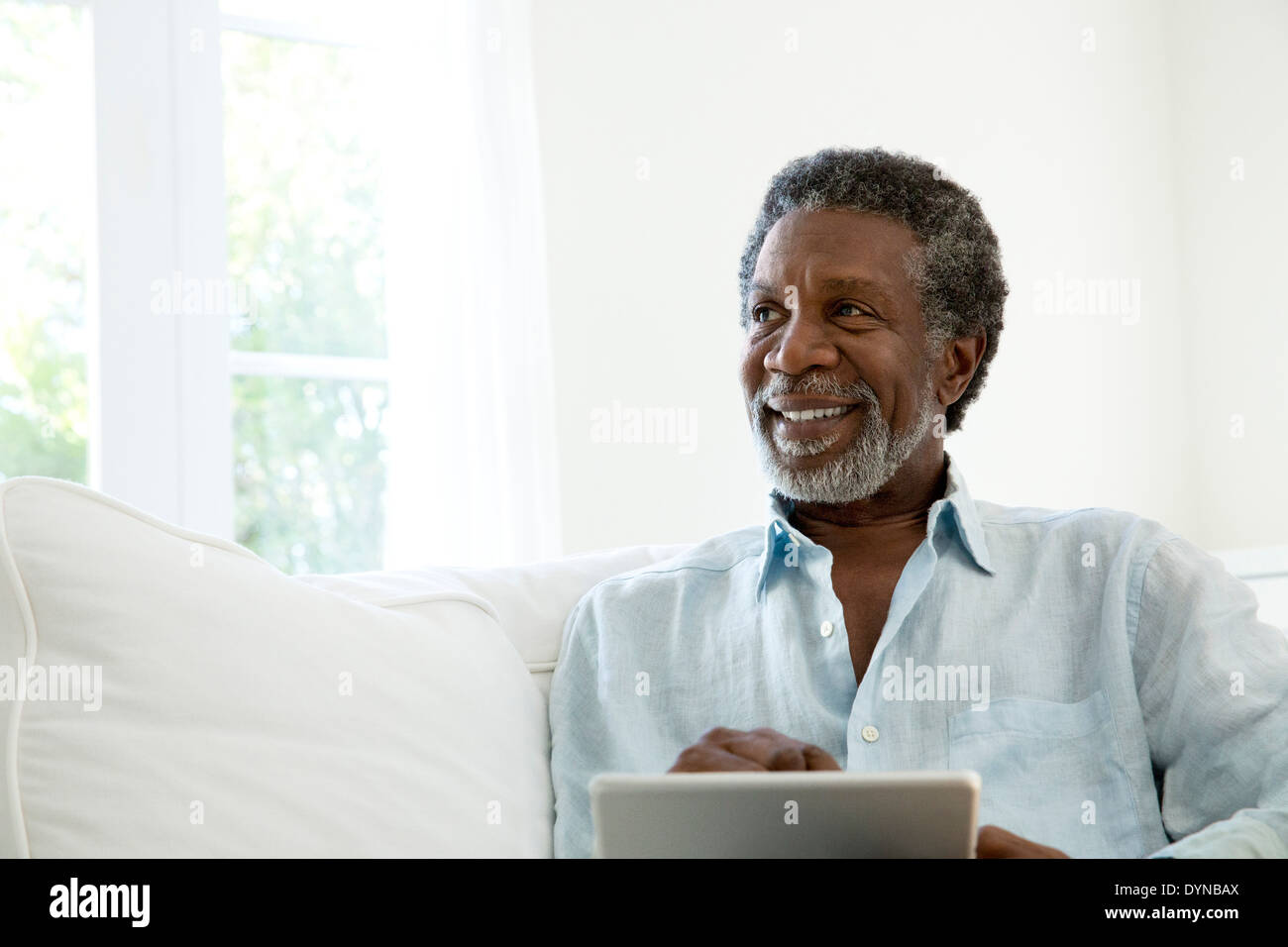 Senior man using digital tablet on sofa Stock Photo