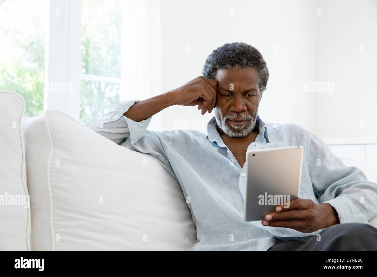Senior man using digital tablet on sofa Stock Photo